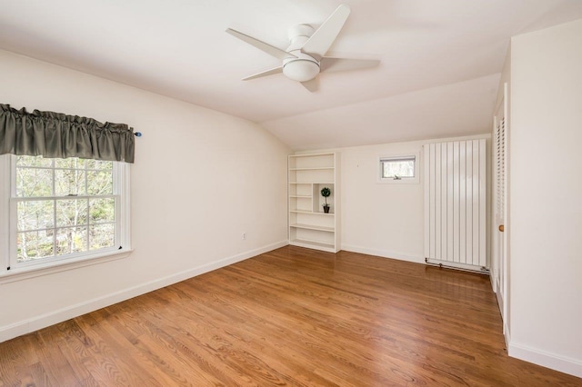 empty room with baseboards, wood finished floors, and lofted ceiling