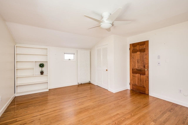 interior space featuring light wood-type flooring, baseboards, ceiling fan, and vaulted ceiling