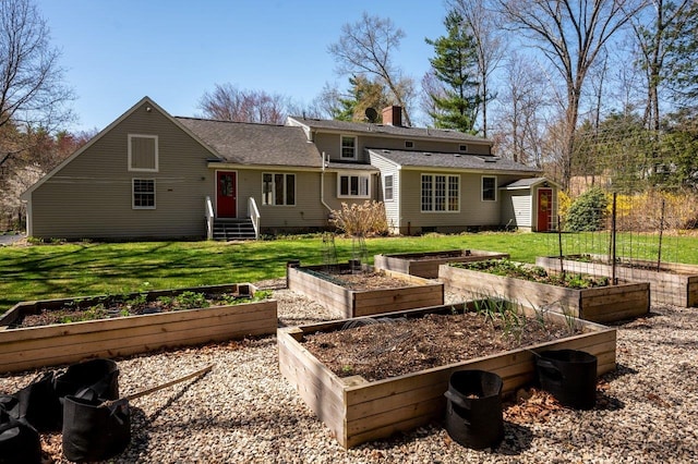 back of property featuring a lawn, roof with shingles, a vegetable garden, and a chimney