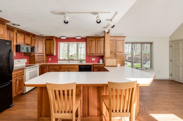 kitchen with light countertops, black appliances, and wood finished floors