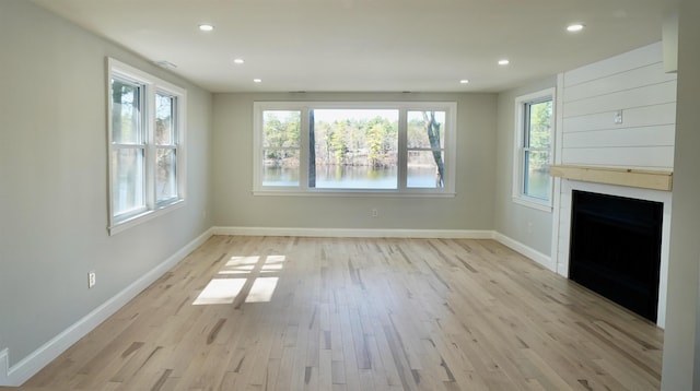 unfurnished living room featuring baseboards, light wood finished floors, recessed lighting, and a large fireplace