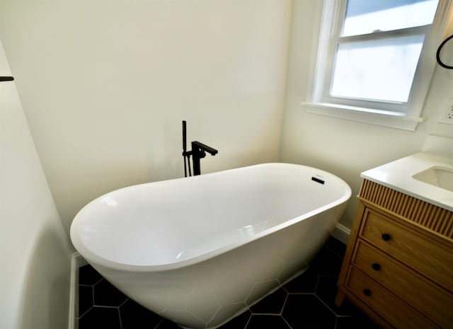 full bathroom with vanity, a freestanding tub, and tile patterned floors