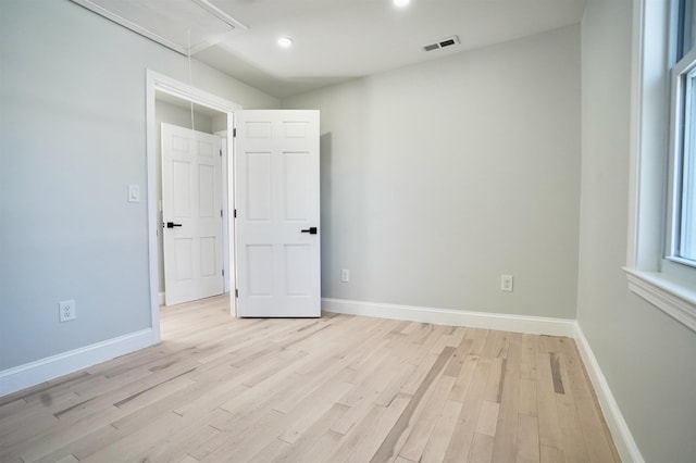 unfurnished room with attic access, visible vents, light wood-type flooring, baseboards, and recessed lighting