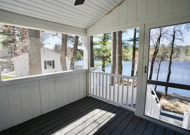 unfurnished sunroom featuring a ceiling fan, a water view, and a healthy amount of sunlight