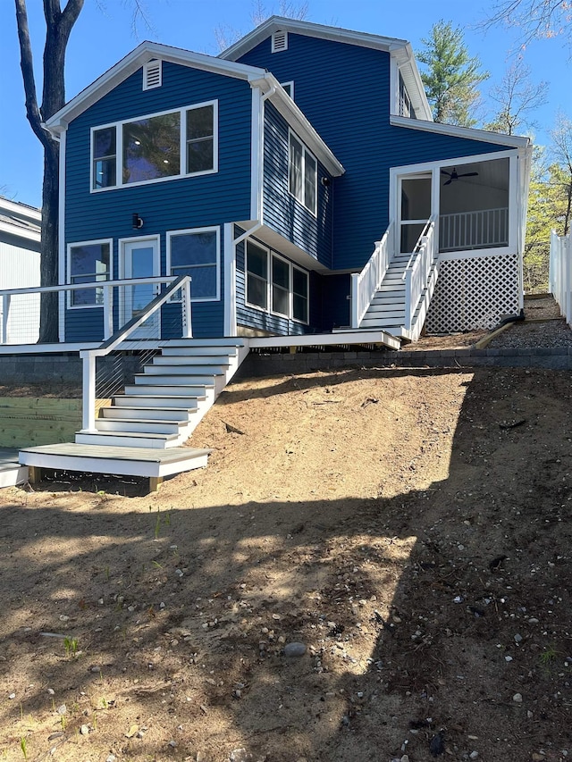 back of property with stairway, ceiling fan, and a sunroom