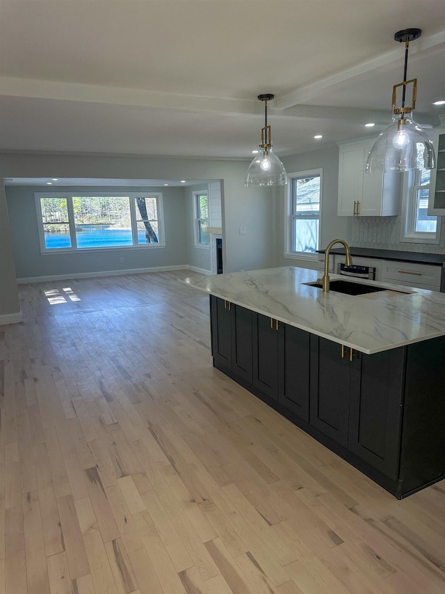 kitchen featuring a sink, dark cabinetry, and light wood-style floors
