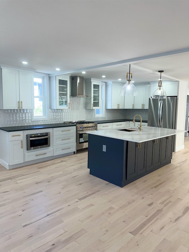 kitchen with wall chimney range hood, appliances with stainless steel finishes, backsplash, and a sink