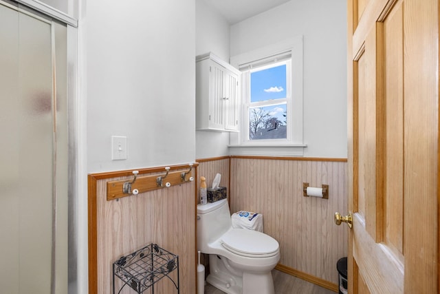 bathroom with toilet and a wainscoted wall