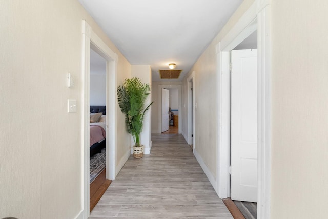 hall with light wood-type flooring and baseboards