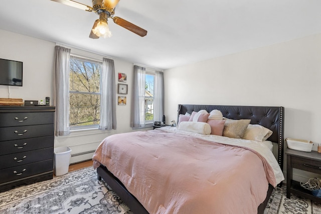 bedroom featuring baseboard heating, a ceiling fan, and wood finished floors
