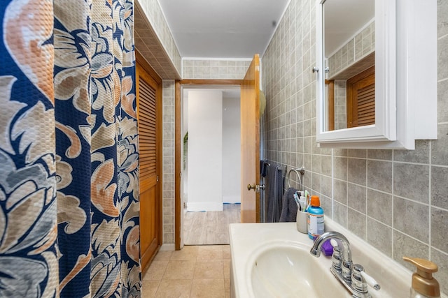 full bath featuring tile patterned flooring, a sink, and tile walls