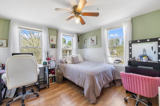 bedroom featuring ceiling fan, wainscoting, and light wood-type flooring