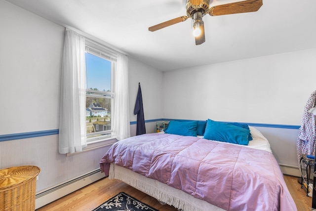 bedroom featuring ceiling fan, baseboard heating, and wood finished floors