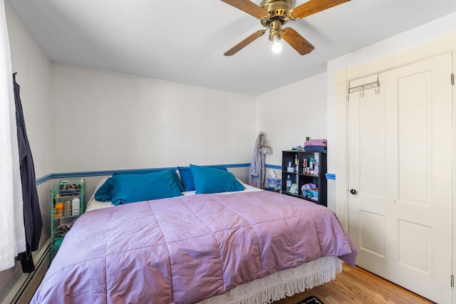 bedroom with a ceiling fan, wood finished floors, and a closet