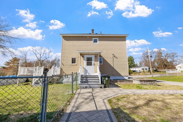 rear view of property featuring a gate, fence, a yard, and entry steps