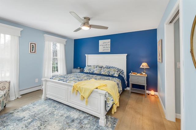 bedroom with baseboards, a ceiling fan, a baseboard heating unit, and wood finished floors
