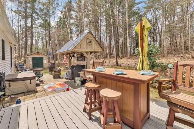 wooden terrace featuring an outbuilding, a shed, and outdoor dry bar