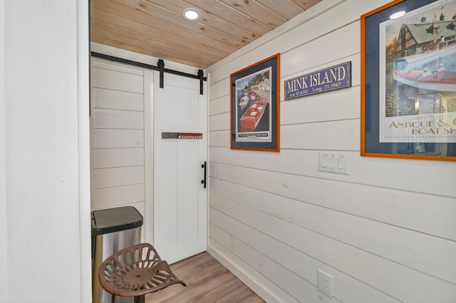 corridor with wood finished floors, wooden walls, recessed lighting, a barn door, and wooden ceiling