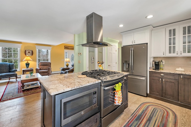 kitchen featuring light stone countertops, stainless steel appliances, light wood finished floors, and island range hood