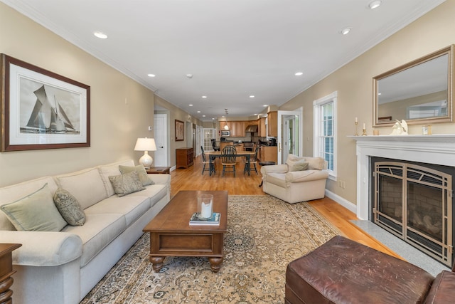 living room with a fireplace with flush hearth, light wood-type flooring, baseboards, ornamental molding, and recessed lighting