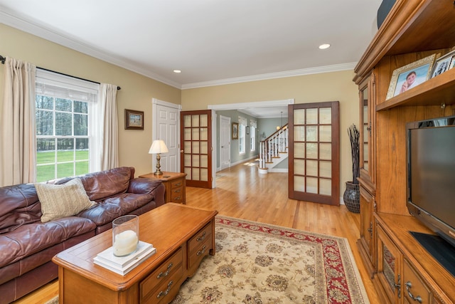 living area with crown molding, french doors, baseboards, light wood-type flooring, and stairway