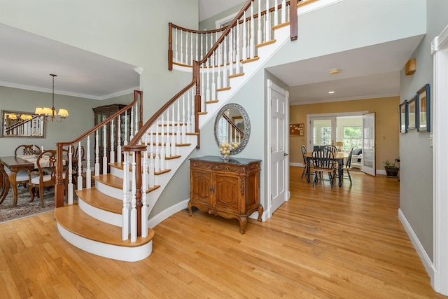 stairway with crown molding, baseboards, a chandelier, and wood finished floors