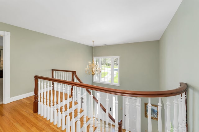 stairway with an inviting chandelier, baseboards, and wood finished floors