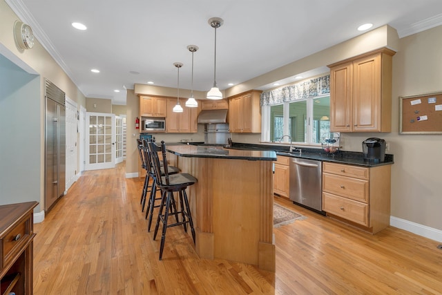 kitchen with under cabinet range hood, stainless steel appliances, baseboards, and light wood-type flooring