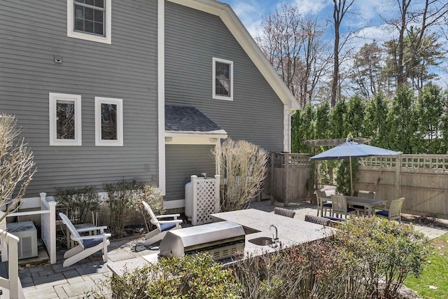 rear view of house with fence, outdoor dining space, and a patio area