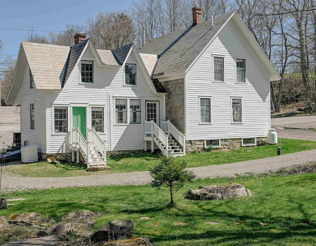 view of front facade with a front yard, a chimney, and entry steps