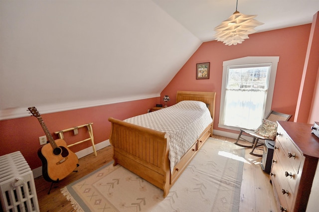 bedroom featuring baseboards, vaulted ceiling, and light wood finished floors