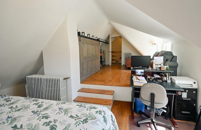 bedroom featuring radiator, lofted ceiling, and hardwood / wood-style floors