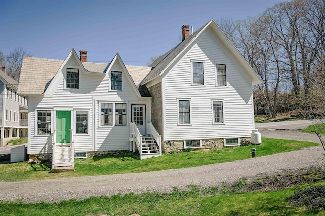rear view of house featuring a yard, a chimney, and entry steps
