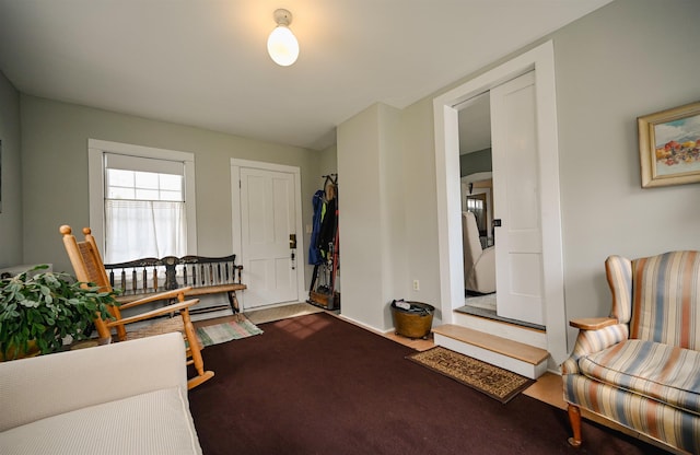 living area with baseboards and dark carpet
