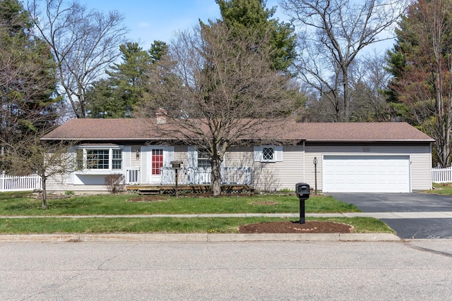 ranch-style house featuring fence, an attached garage, a front lawn, and aphalt driveway