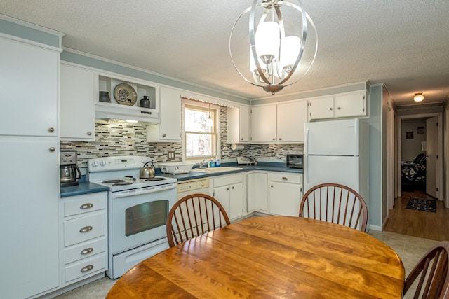 kitchen with dark countertops, a sink, ventilation hood, a notable chandelier, and white appliances