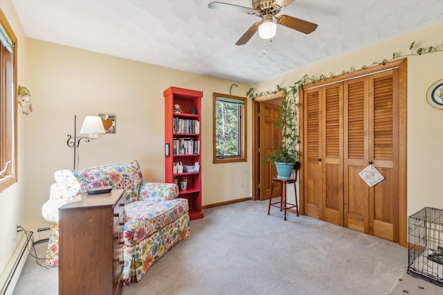 living area with baseboards, a baseboard radiator, a ceiling fan, and carpet flooring