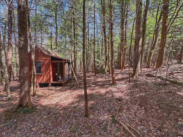 view of yard featuring an outdoor structure and a wooded view