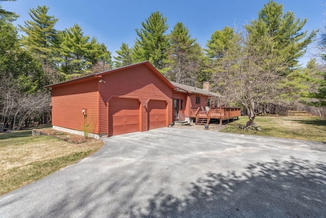view of front of house featuring an attached garage, a front lawn, a deck, a chimney, and driveway