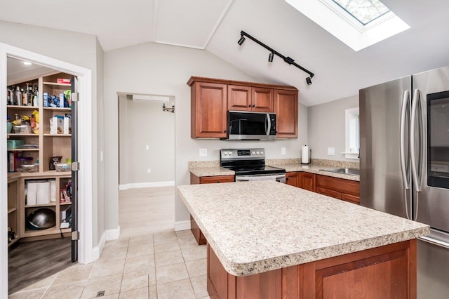 kitchen featuring light countertops, stainless steel appliances, brown cabinets, and lofted ceiling with skylight