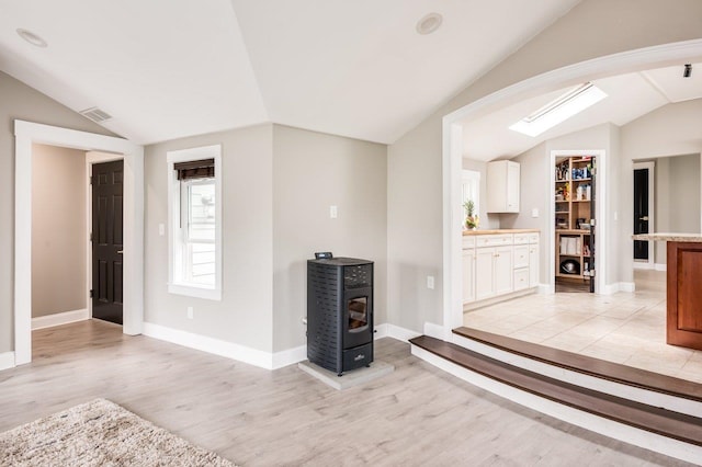 11 Post Rd, North Hampton, NH 03862 - living room featuring vaulted ceiling, light wood finished floors, baseboards, a wood stove, and arched walkways