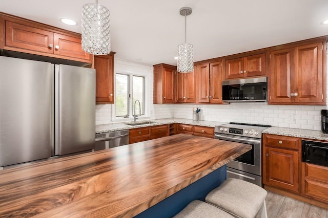 11 Post Rd, North Hampton, NH 03862 - kitchen with stainless steel appliances, butcher block counters, a sink, decorative backsplash, and brown cabinetry