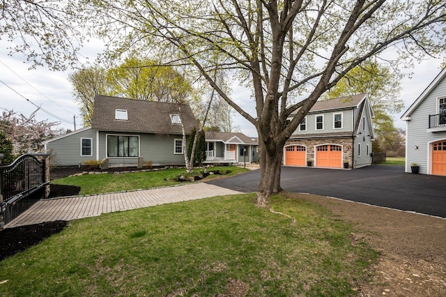 view of front of house featuring stone siding, an attached garage, a front yard, and aphalt driveway