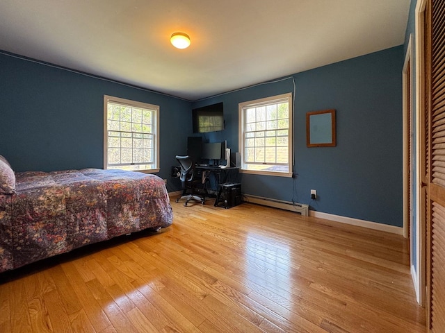 bedroom featuring baseboards, a baseboard radiator, multiple windows, and hardwood / wood-style floors