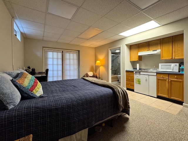 bedroom featuring light tile patterned floors, ensuite bathroom, light carpet, and a drop ceiling