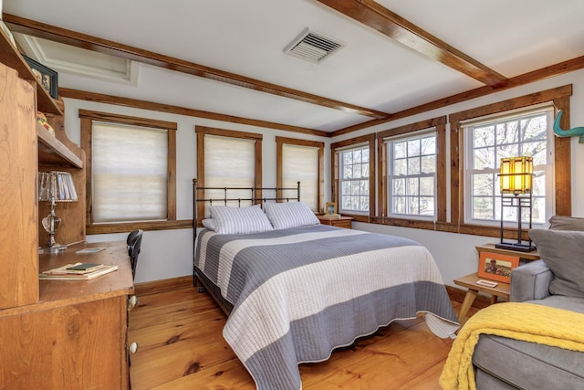 bedroom with beamed ceiling, visible vents, and light wood-style floors