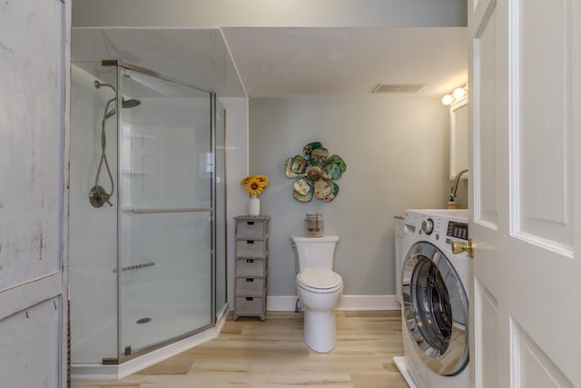 bathroom with washer / clothes dryer, visible vents, a stall shower, wood finished floors, and toilet