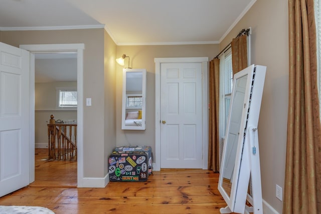corridor featuring crown molding, baseboards, wood-type flooring, and an upstairs landing