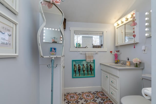 bathroom with baseboards, vanity, and toilet
