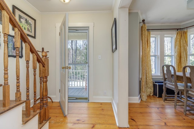 foyer with baseboards, ornamental molding, light wood-style flooring, and stairway